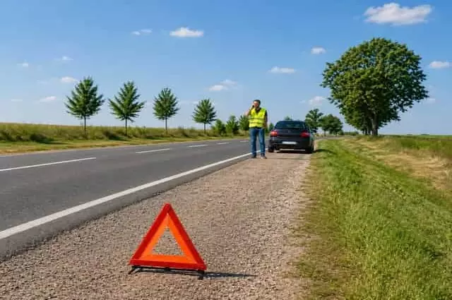 Defekt esetén álljon meg biztonságosan és telefonáljon a védett zónából! Defekt esetén az út szélén telefonáló, láthatósági mellényt viselő autós elakadásjelző háromszöggel