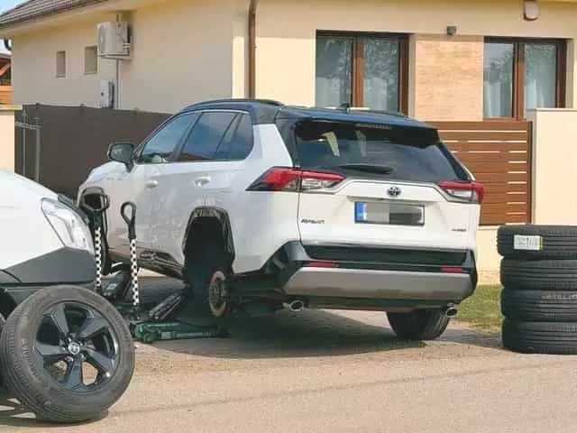 Nyári gumiszett felhelyezése fehér Toyota RAV4-re Nyári kerékcsere kocsifelhajtón, otthon fehér Toyota RAV4 személygépkocsin
